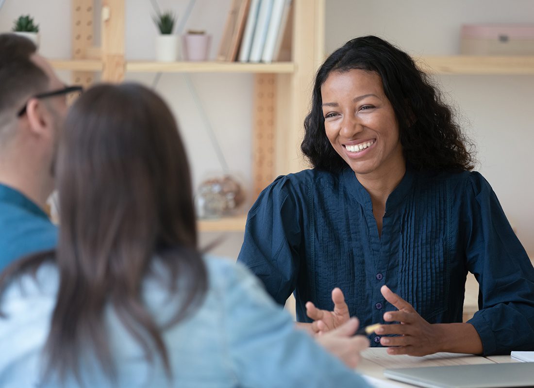 About Our Agency - Friendly Agent Speaks With a Couple at Her Office